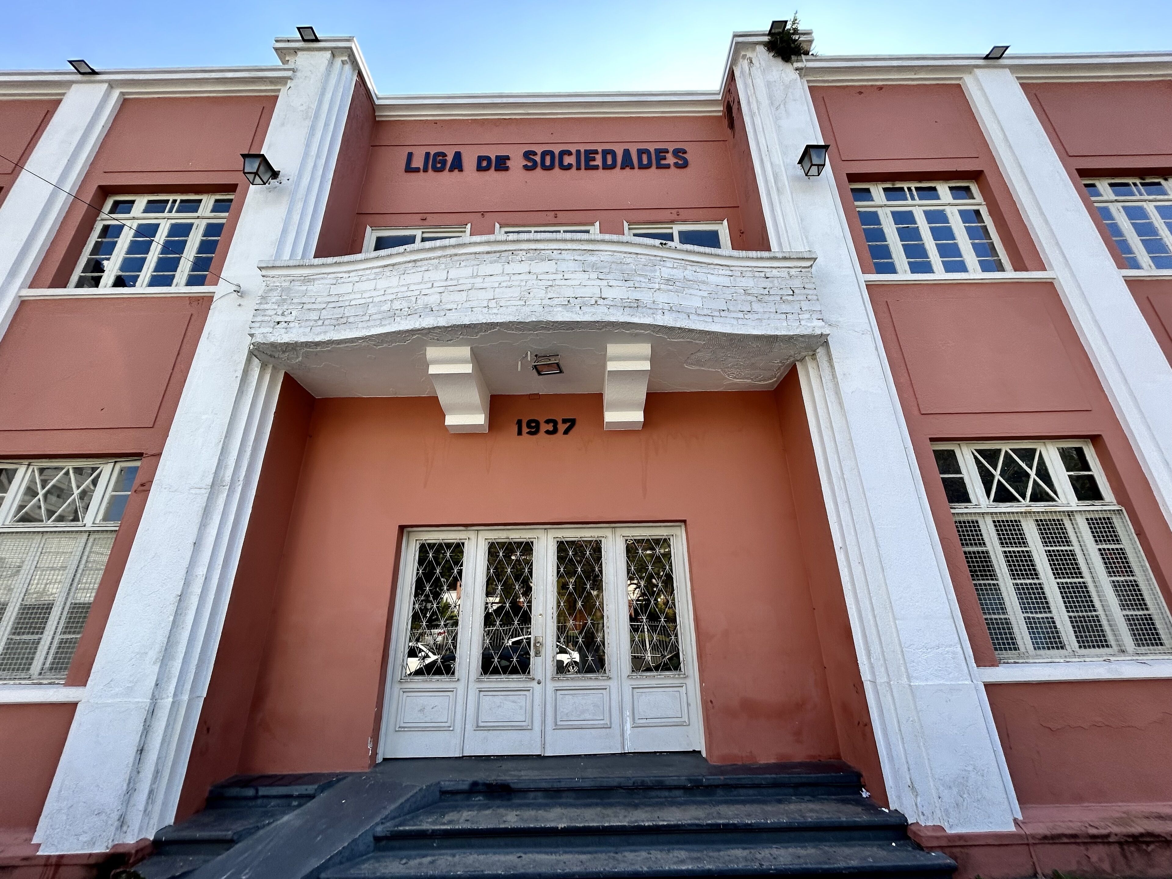 A building with a sign reading "LIGA DE SOCIEDADES" and the year "1937" above the entrance.