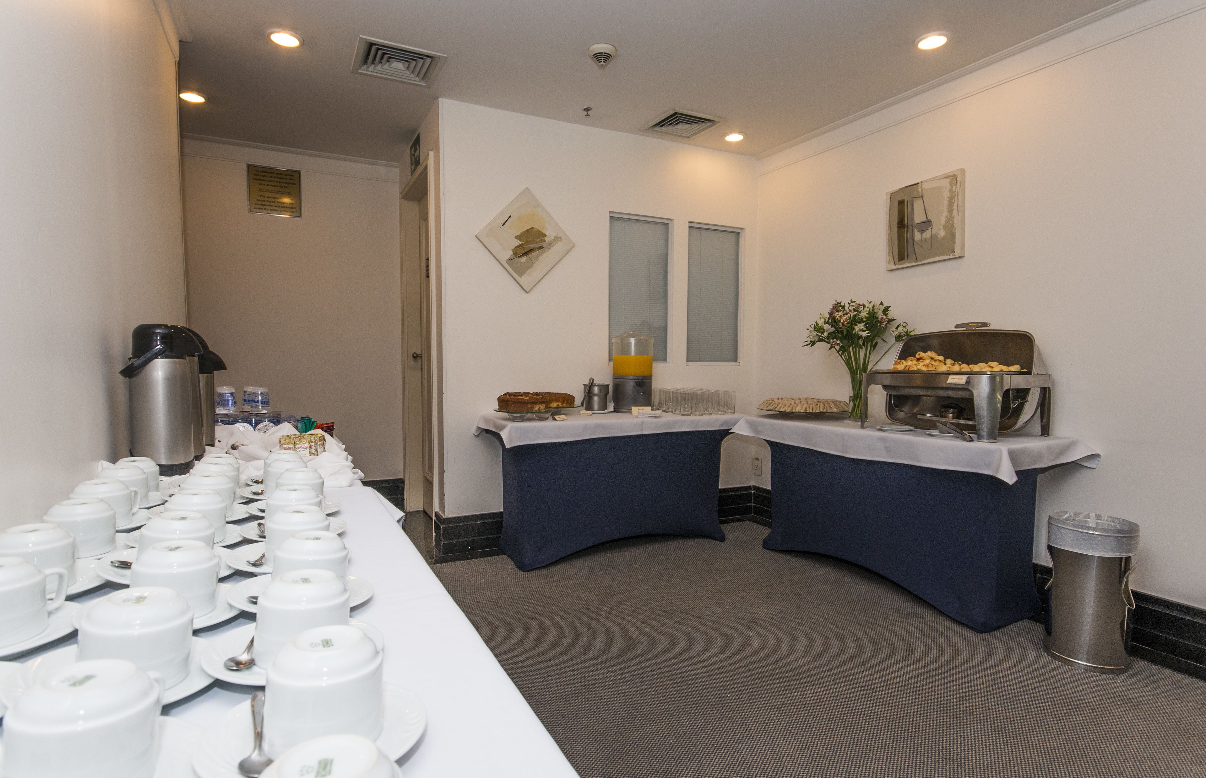 A breakfast buffet setup with multiple serving stations, a coffee machine, and a trash can.