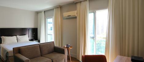 A hotel room with a bed, a sofa, a table, and a desk.