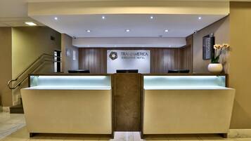 Zona de recepción con mostrador, escalera y cartel del Hotel Ejecutivo Transamerica.