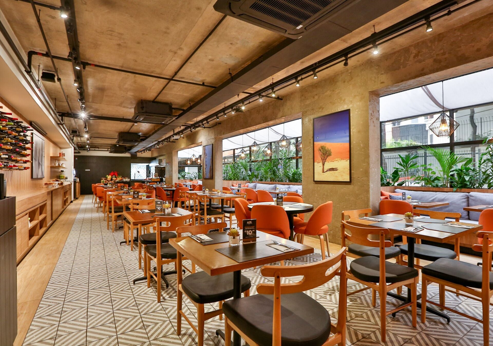 A restaurant with a long counter, multiple tables with orange chairs, and a patterned floor.