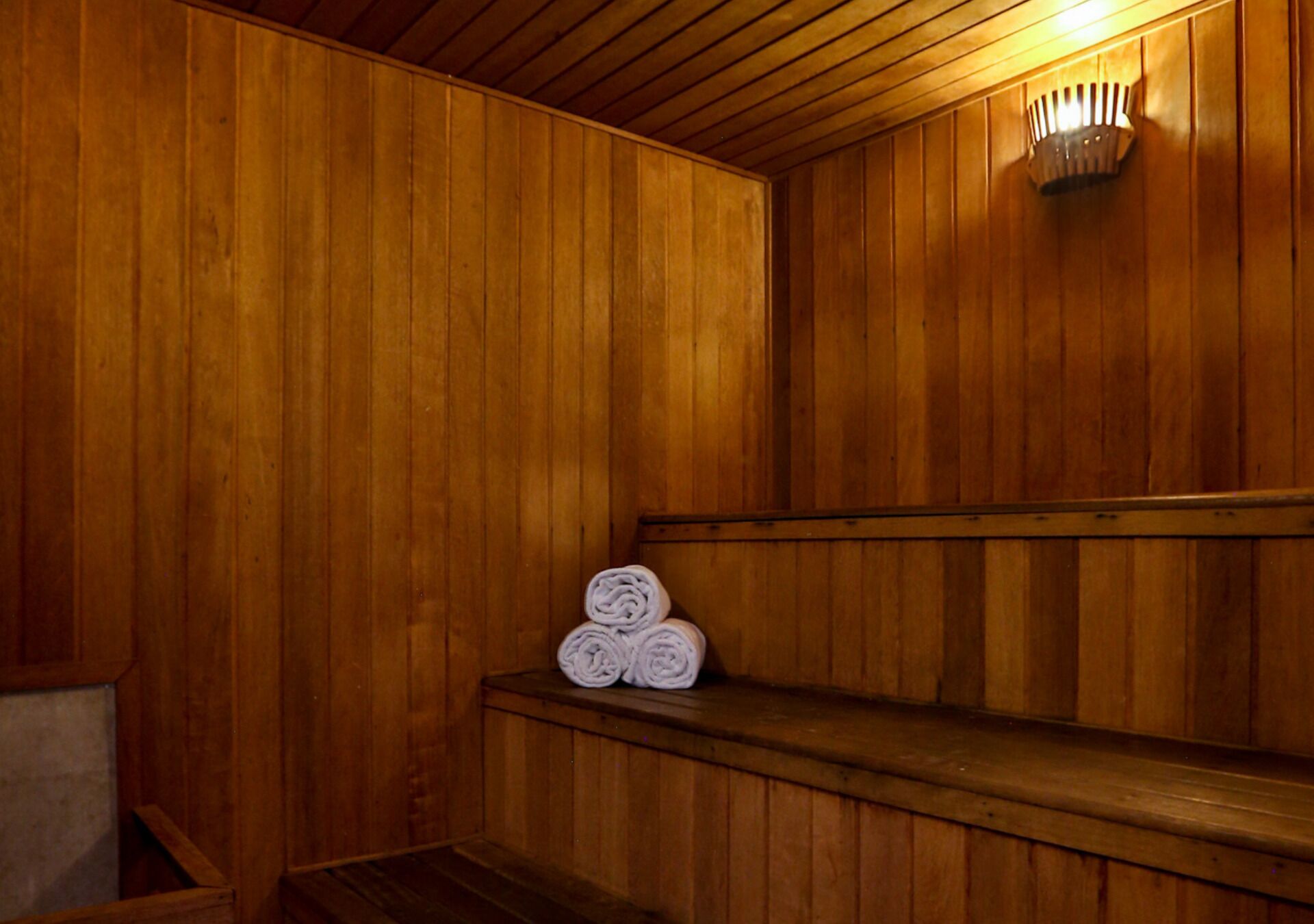 A wooden sauna with benches and rolled towels.