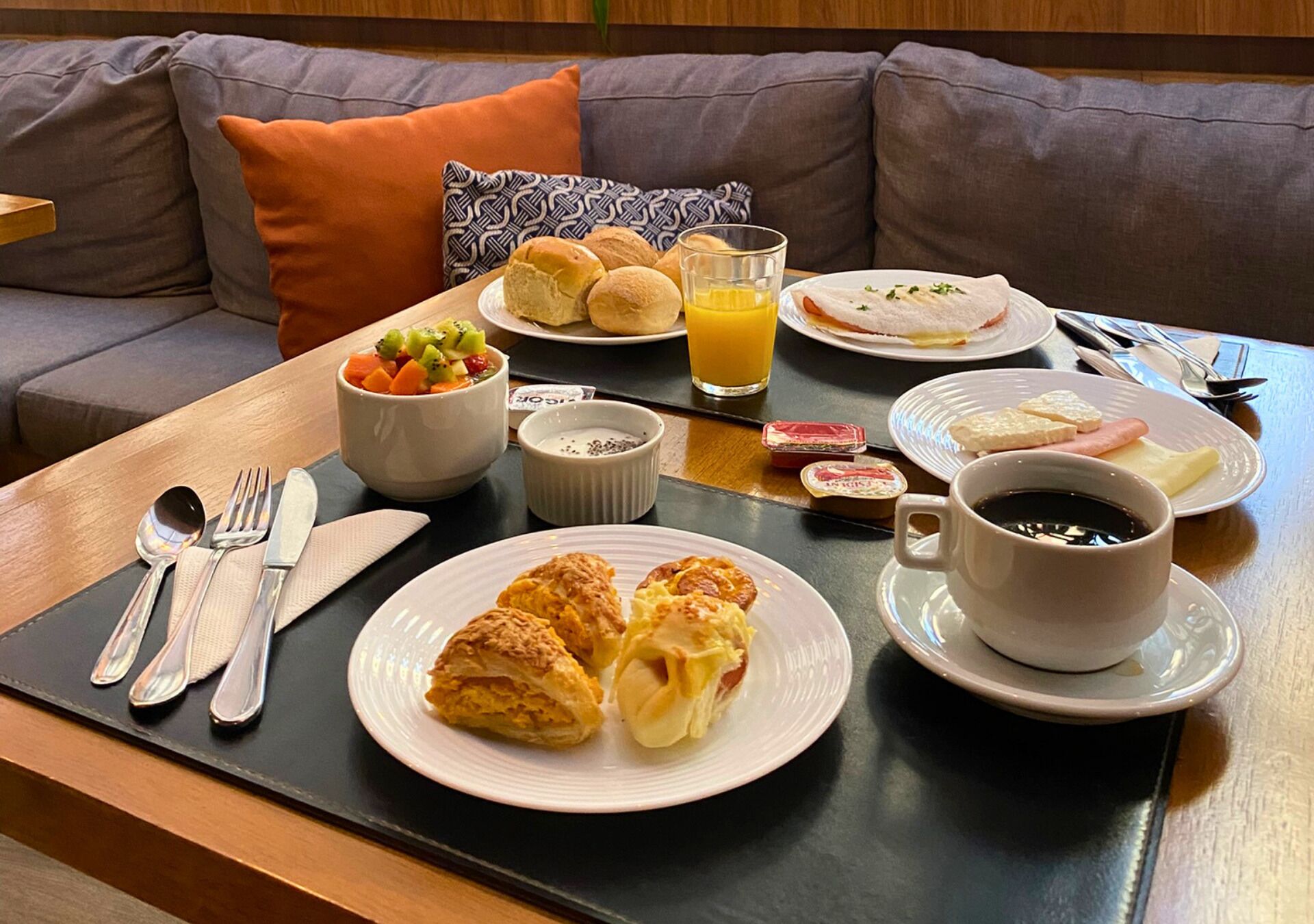 A breakfast tray with croissants, pastries, and a glass of orange juice on a table.