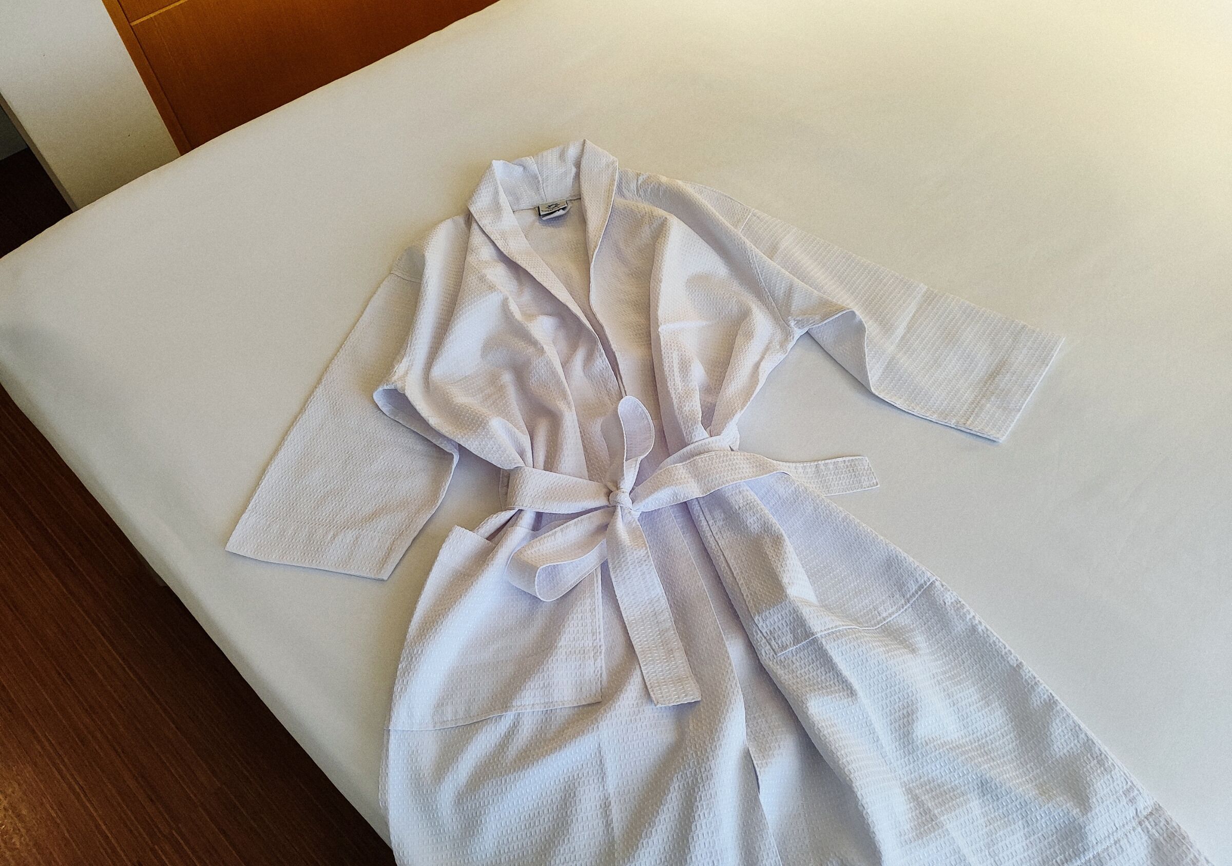 Un robe blanco extendido sobre una cama con cabecera de madera.