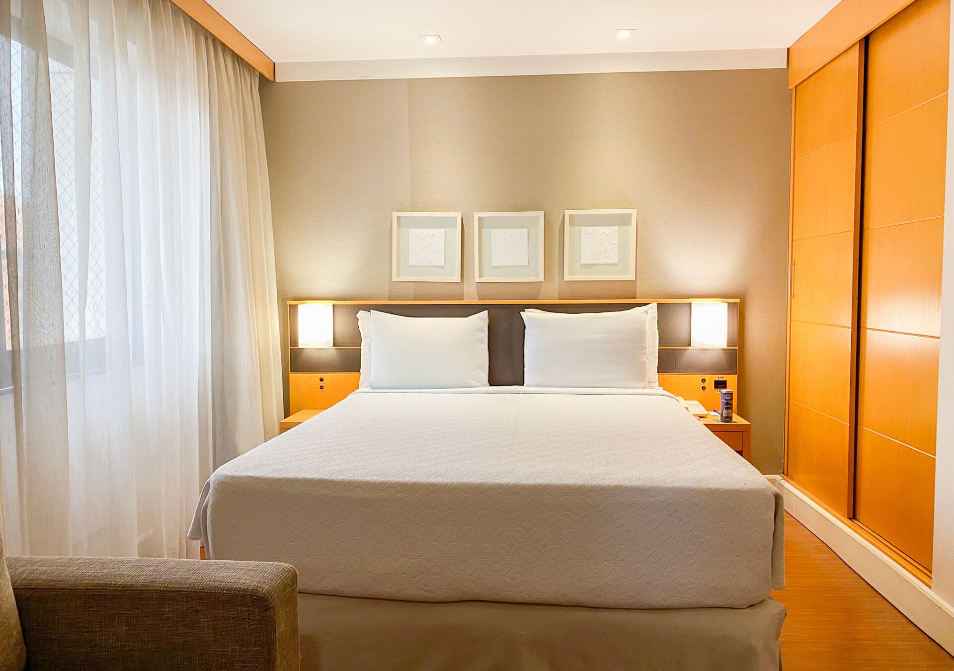 Una camera d'albergo con un letto grande, un comodino, una sedia e un armadio.