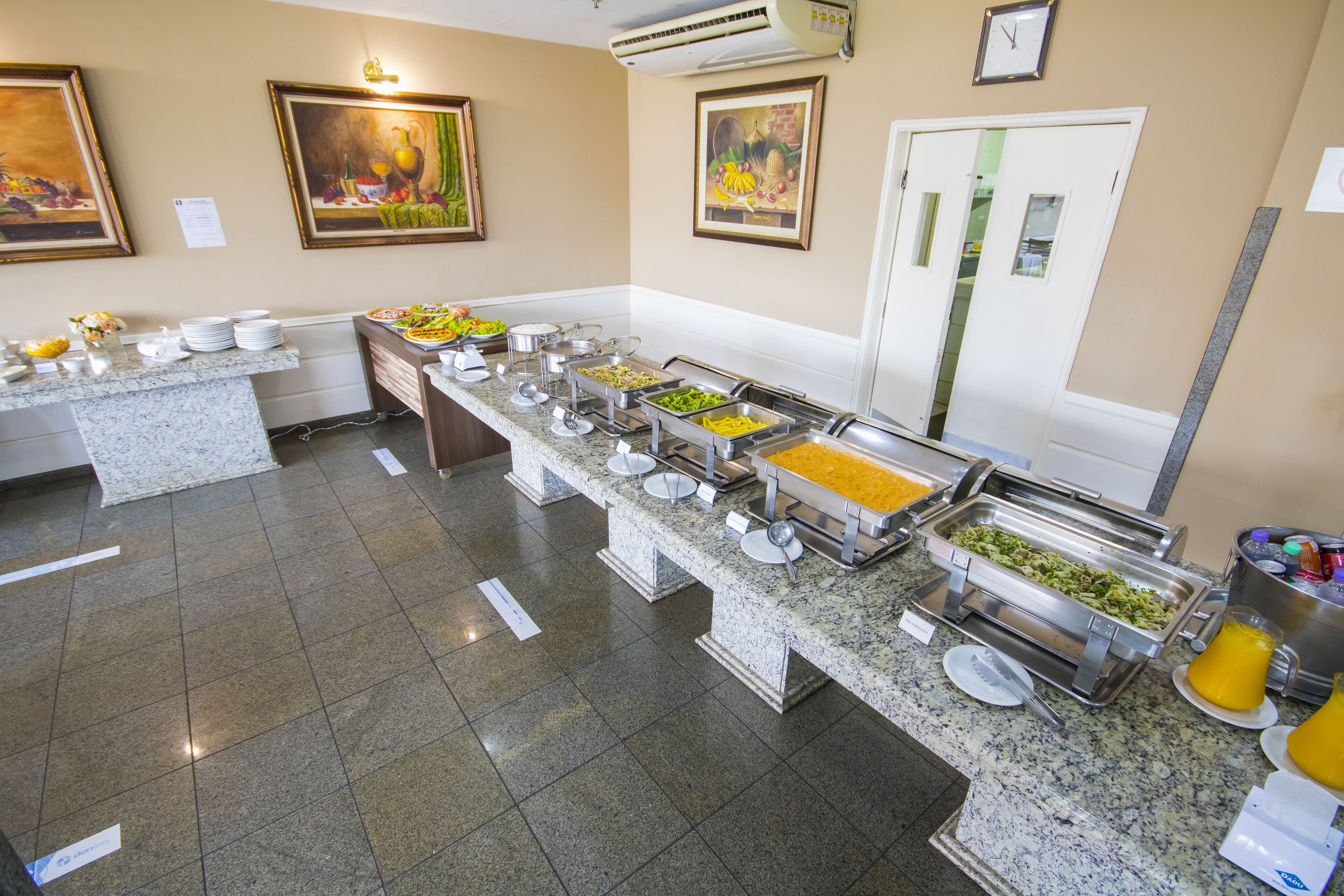 A buffet setup with multiple food stations, a clock, and artwork on the walls.