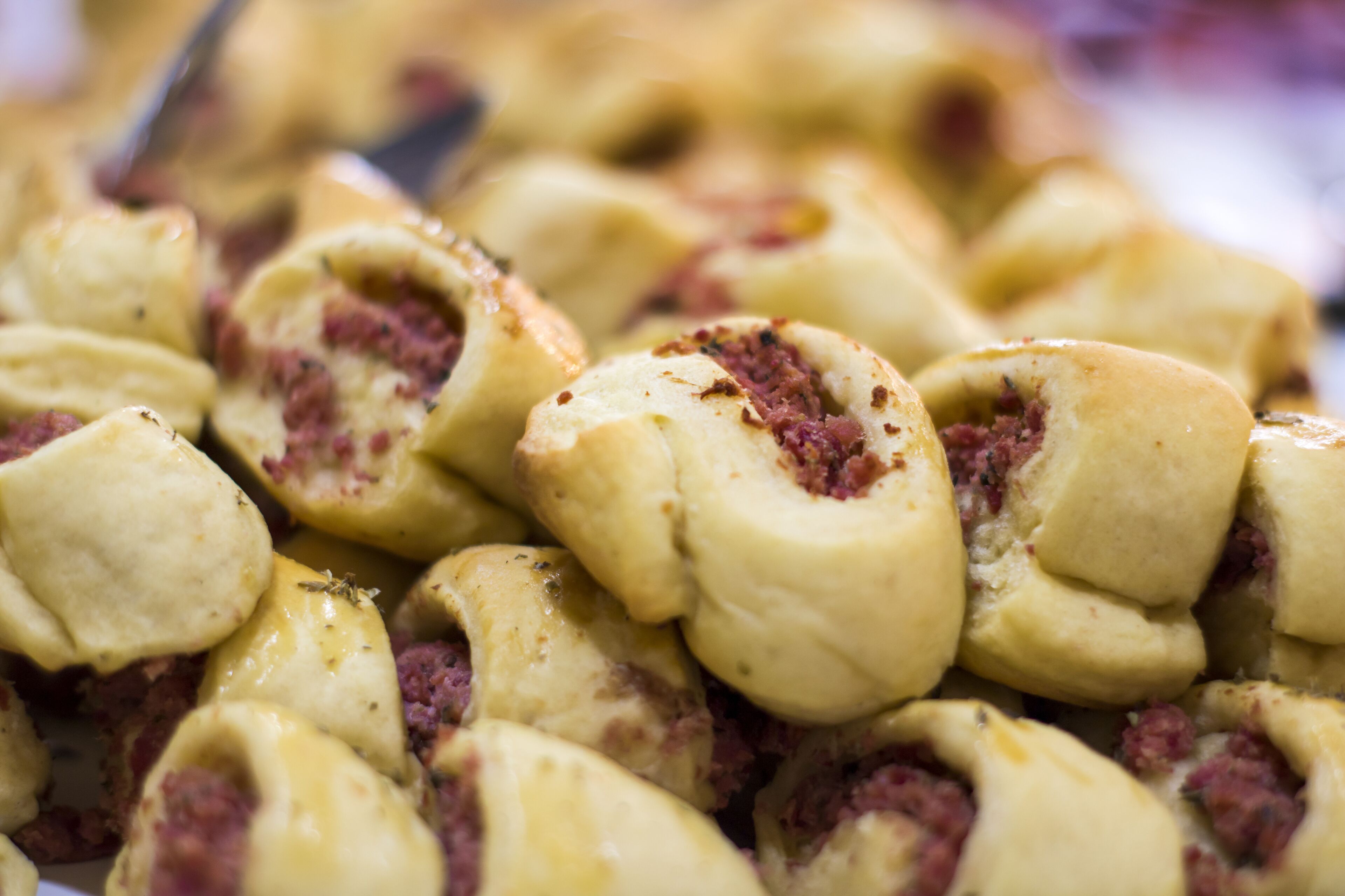 Primer plano de un alimento, probablemente un pastel o producto de repostería, con corteza dorada y relleno visible.