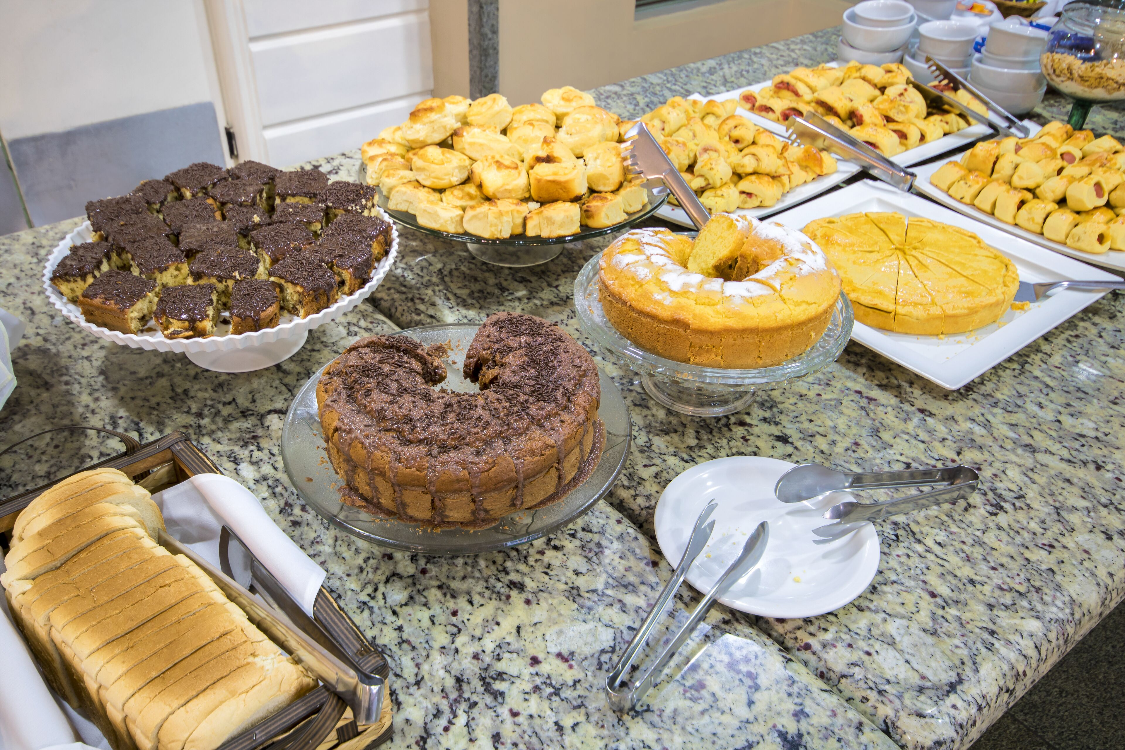 A buffet table with various desserts including cakes and pastries.