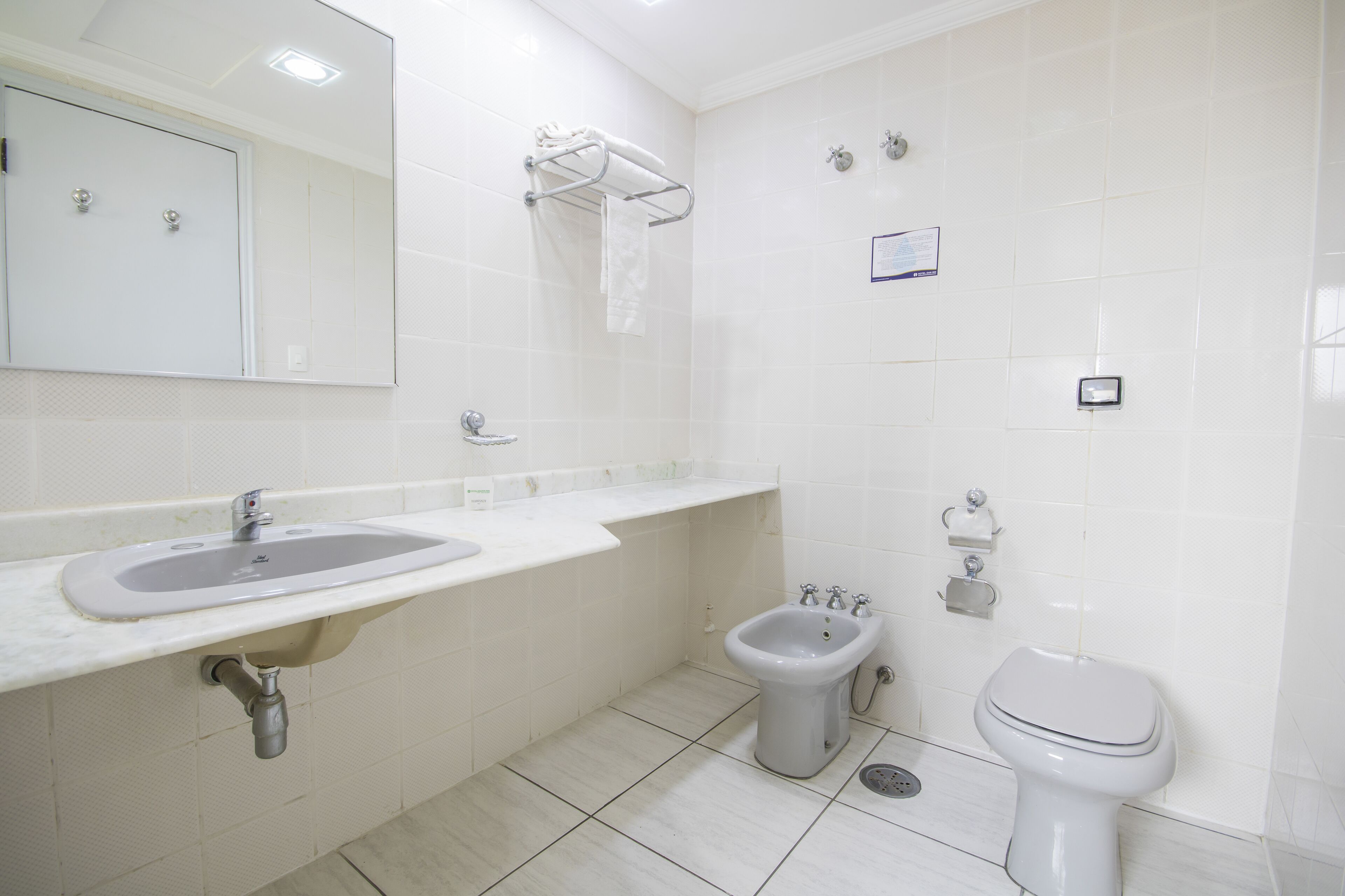 Un bany modern amb un lavabo, vàter, vàter auxiliar i un mirall.