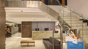 Un vestíbulo moderno con una recepción, zona de estar y una escalera.