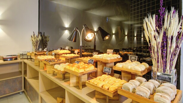 Una vitrina de panadería con diversos productos horneados y un arreglo floral decorativo.