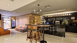 Un interior moderno con una zona de estar, un bar y un refrigerador lleno de bebidas.