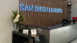 A reception desk with a sign reading "SAN DIEGO LOURDES" and a wheelchair accessibility symbol. - San Diego Suites Lourdes (Belo Horizonte)