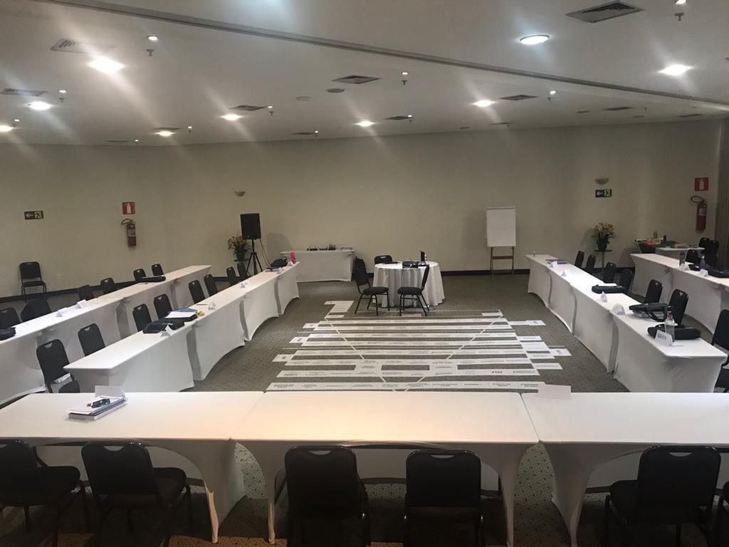 Een vergaderzaal met lange tafels, stoelen, een whiteboard en een spreekgestalte.