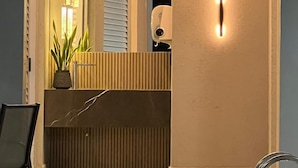 A reception area with a modern design, featuring a reception desk, a potted plant, and a security camera. - San Diego Suites Lourdes (Belo Horizonte)