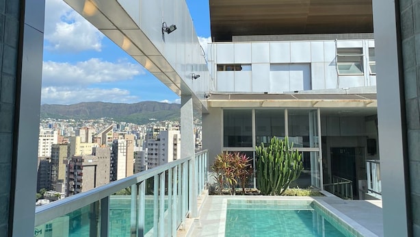 A modern building with a rooftop pool and a view of a cityscape. - San Diego Suites Lourdes (Belo Horizonte)