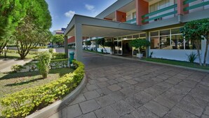 A modern building with a covered entrance, a landscaped garden, and a clear sky. - Hotel Deville Express Guaíra (Guaira)