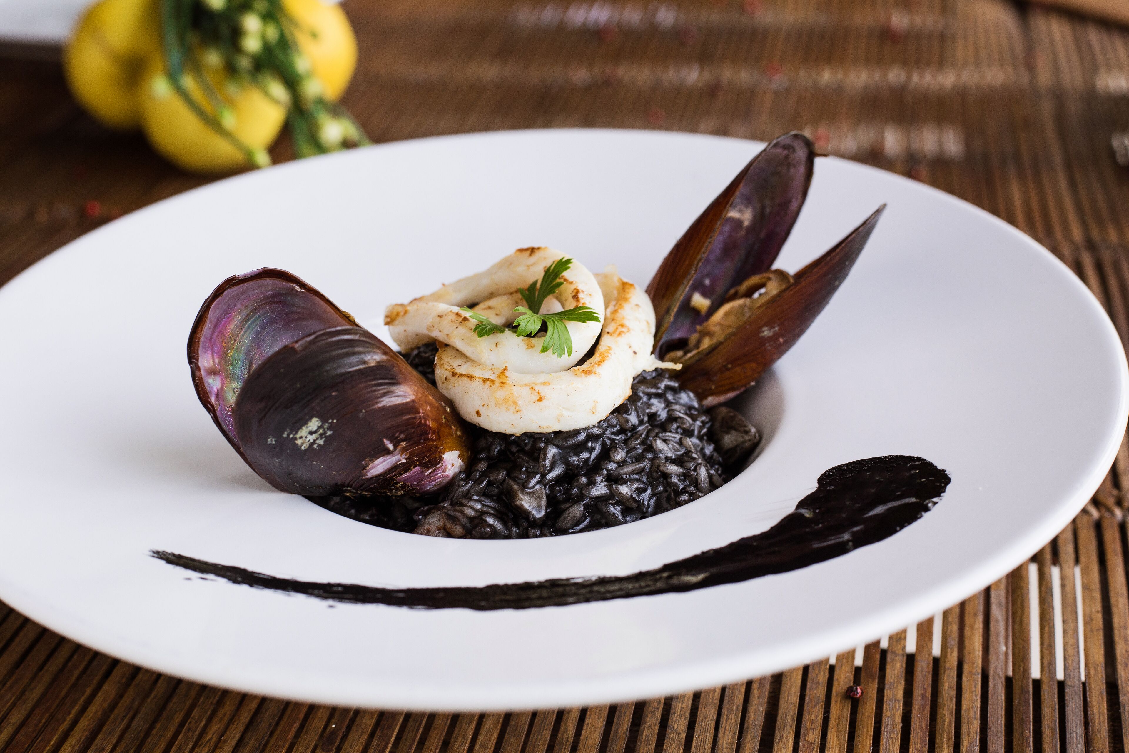A plate of food with mussels and a white sauce, served on a white plate.