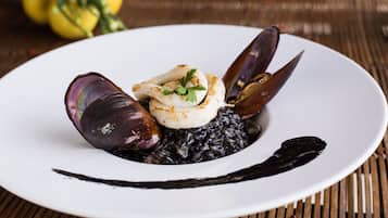 A plate of food with mussels and a white sauce, served on a white plate.