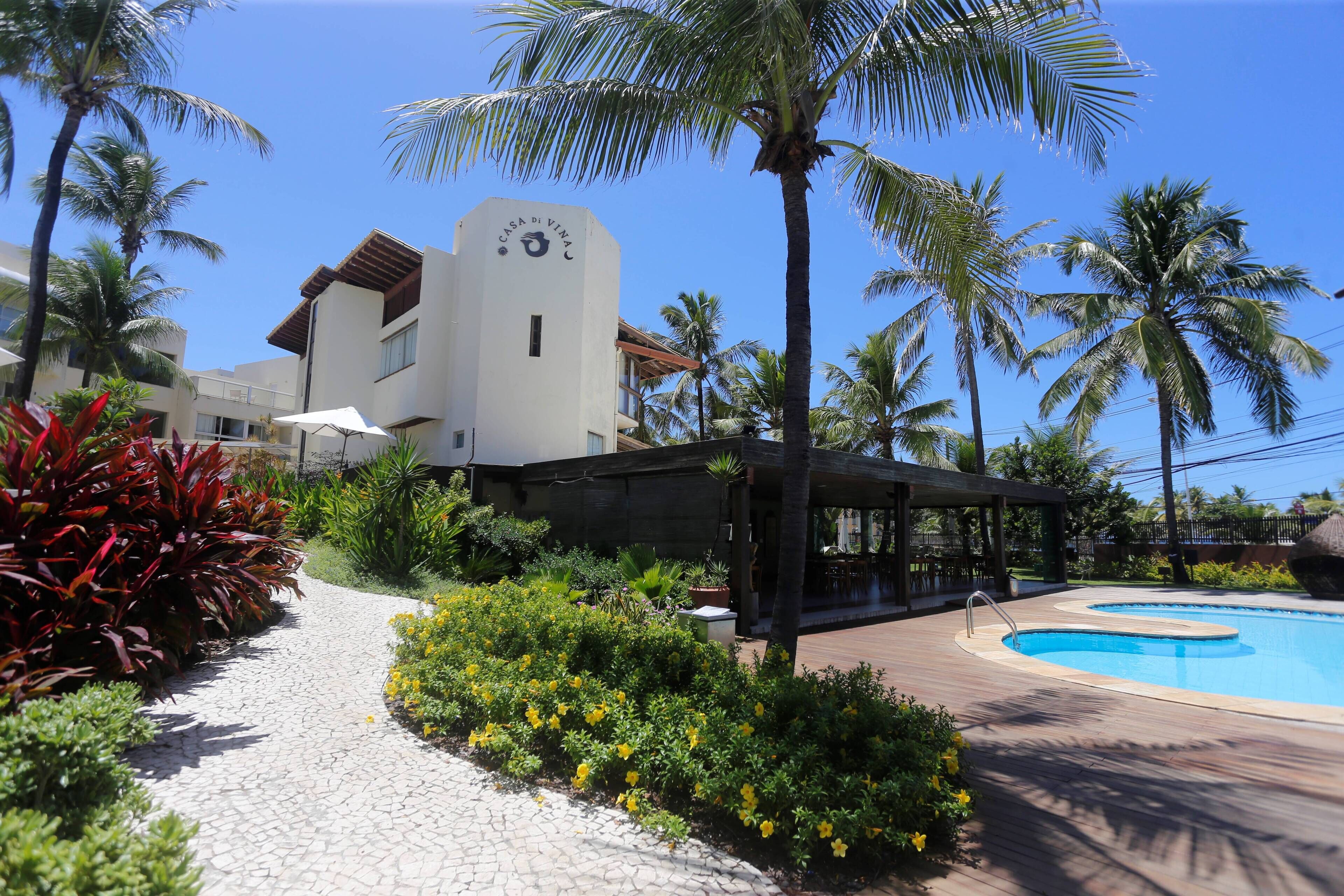 A resort with a swimming pool, palm trees, and a building with a sign reading "Casa de Vina".
