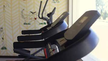 A stationary bike in a room with a patterned wall and a window.