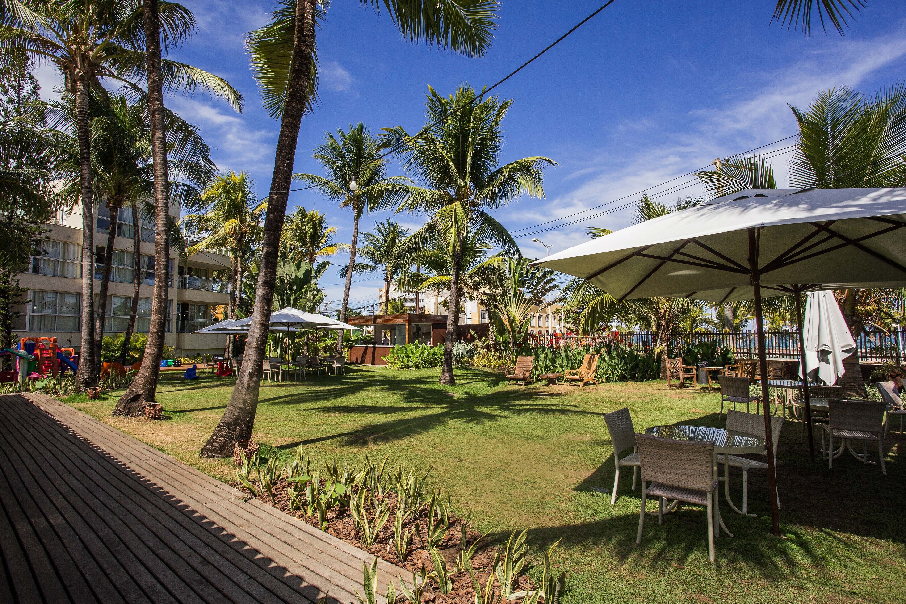 A resort courtyard with palm trees, outdoor seating, and a pool area.