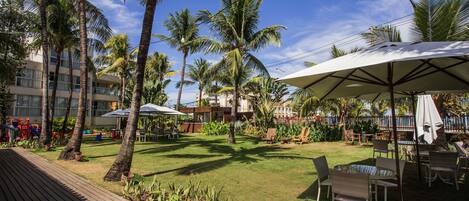 A resort courtyard with palm trees, outdoor seating, and a pool area.