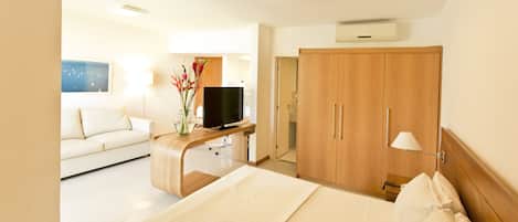 Une chambre d’hôtel avec un lit, un téléviseur posé sur un bureau, une armoire et un canapé.