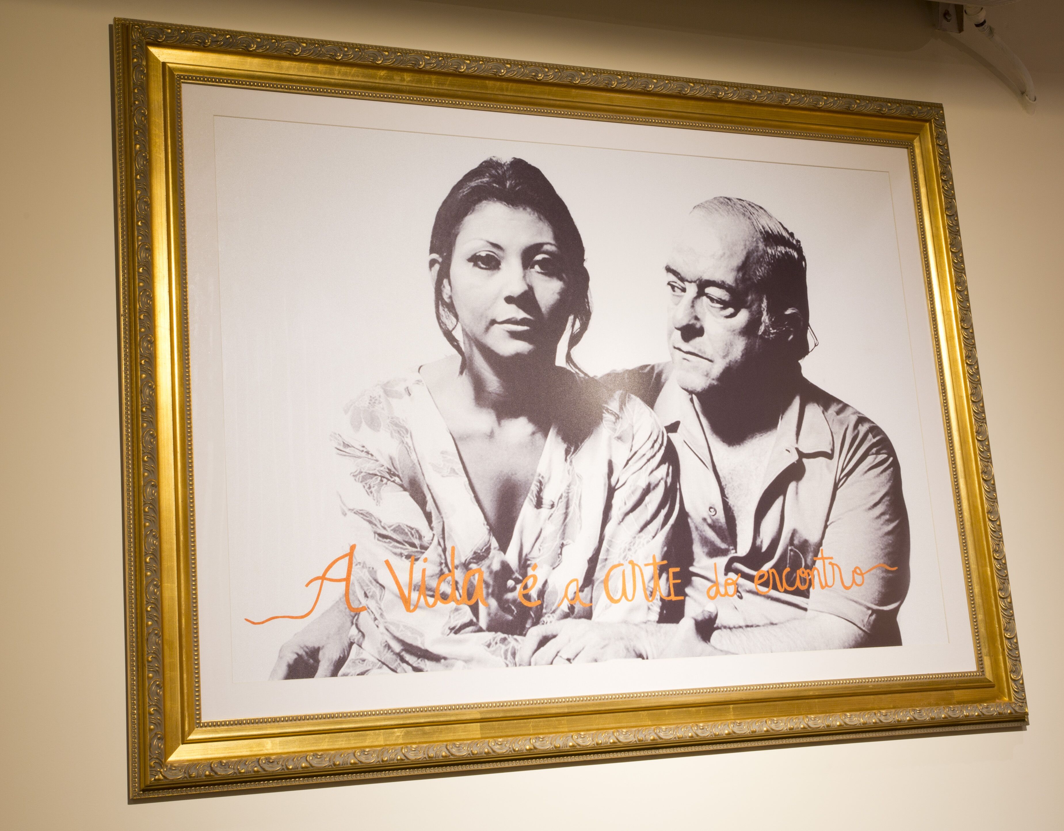 Een lijstfoto met een sierlijk gouden frame, waarop twee personen staan afgebeeld.