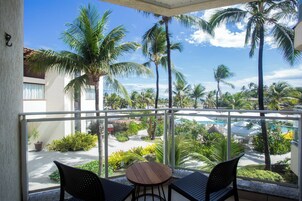 Un balcón con vista a una piscina y palmeras.