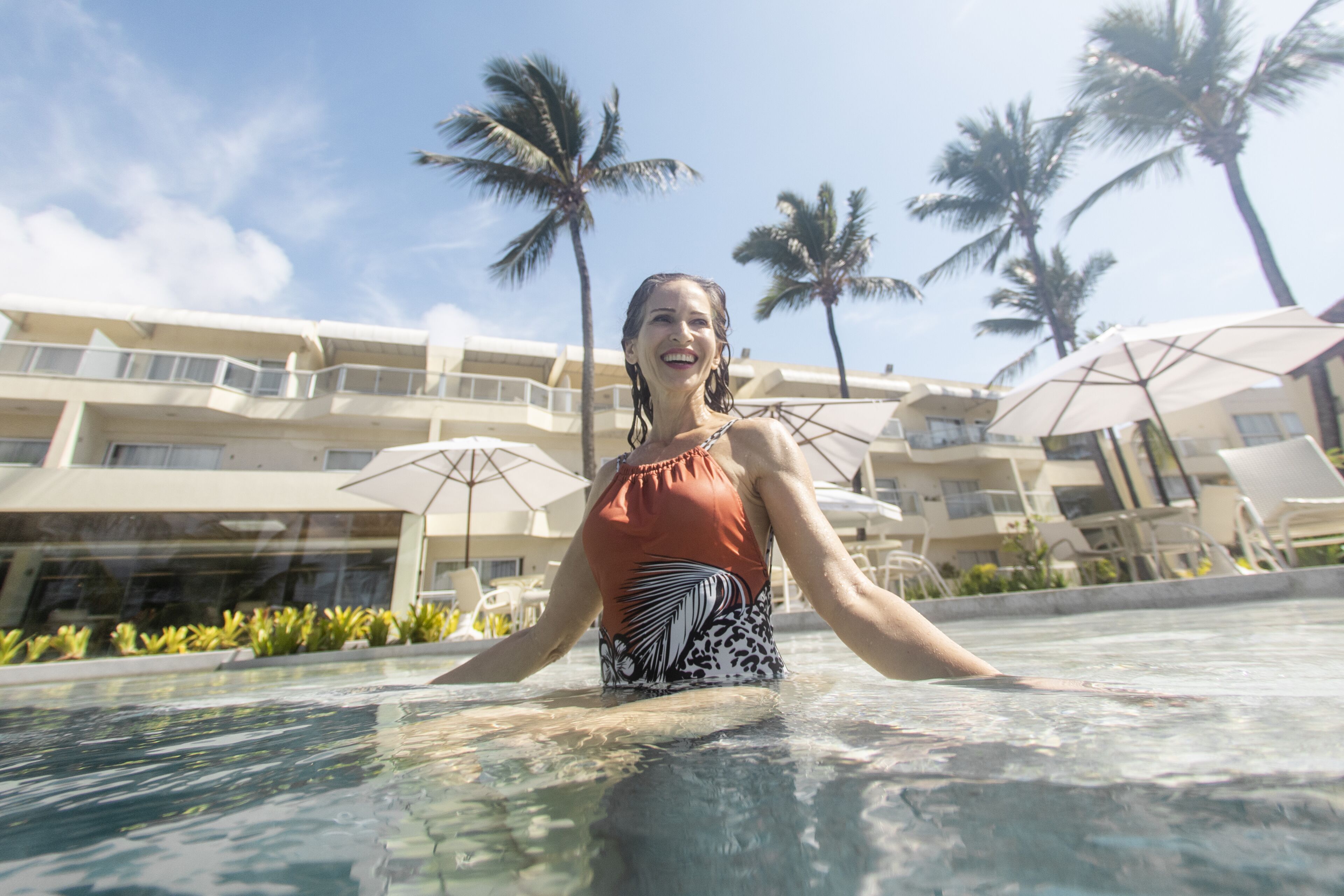 Eine Person im Pool, im Hintergrund ein Hotelgebäude.