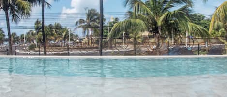 Una piscina al aire libre, sombrillas, sillones reclinables de piscina