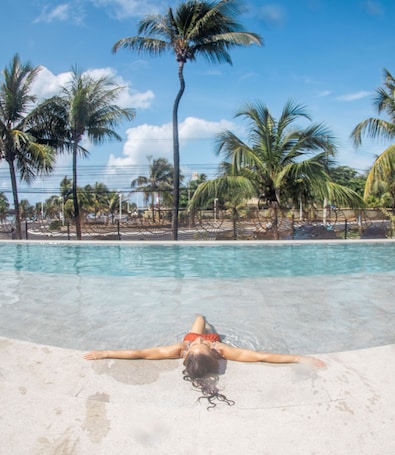 Una piscina al aire libre, sombrillas, sillones reclinables de piscina