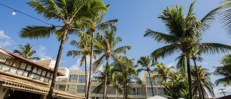 A hotel with a pool area, palm trees, and outdoor seating.
