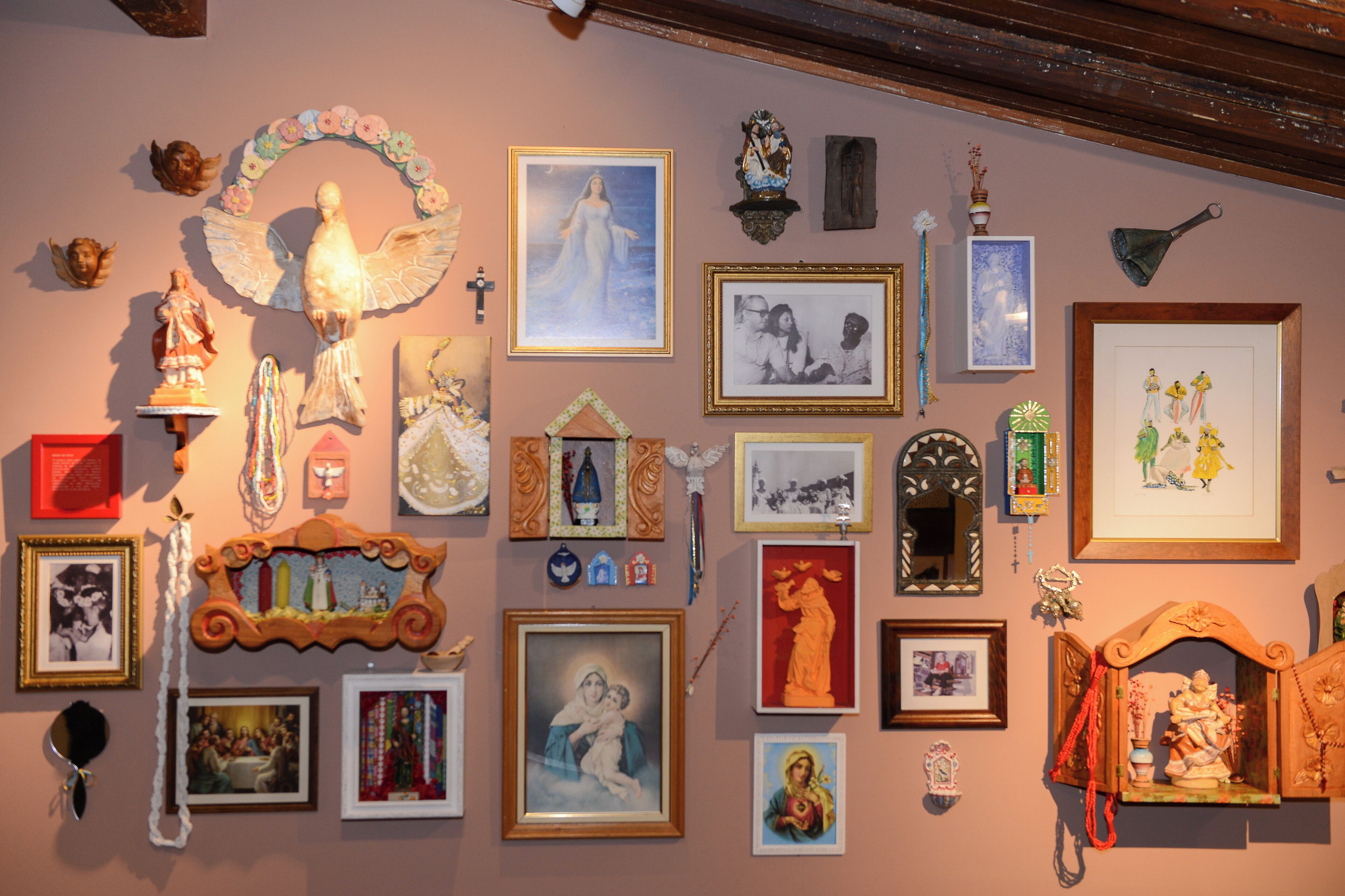A wall adorned with various religious and cultural artifacts, including framed pictures, statues, and decorative items.