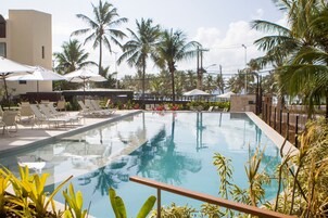 Una piscina al aire libre, sombrillas, sillones reclinables de piscina