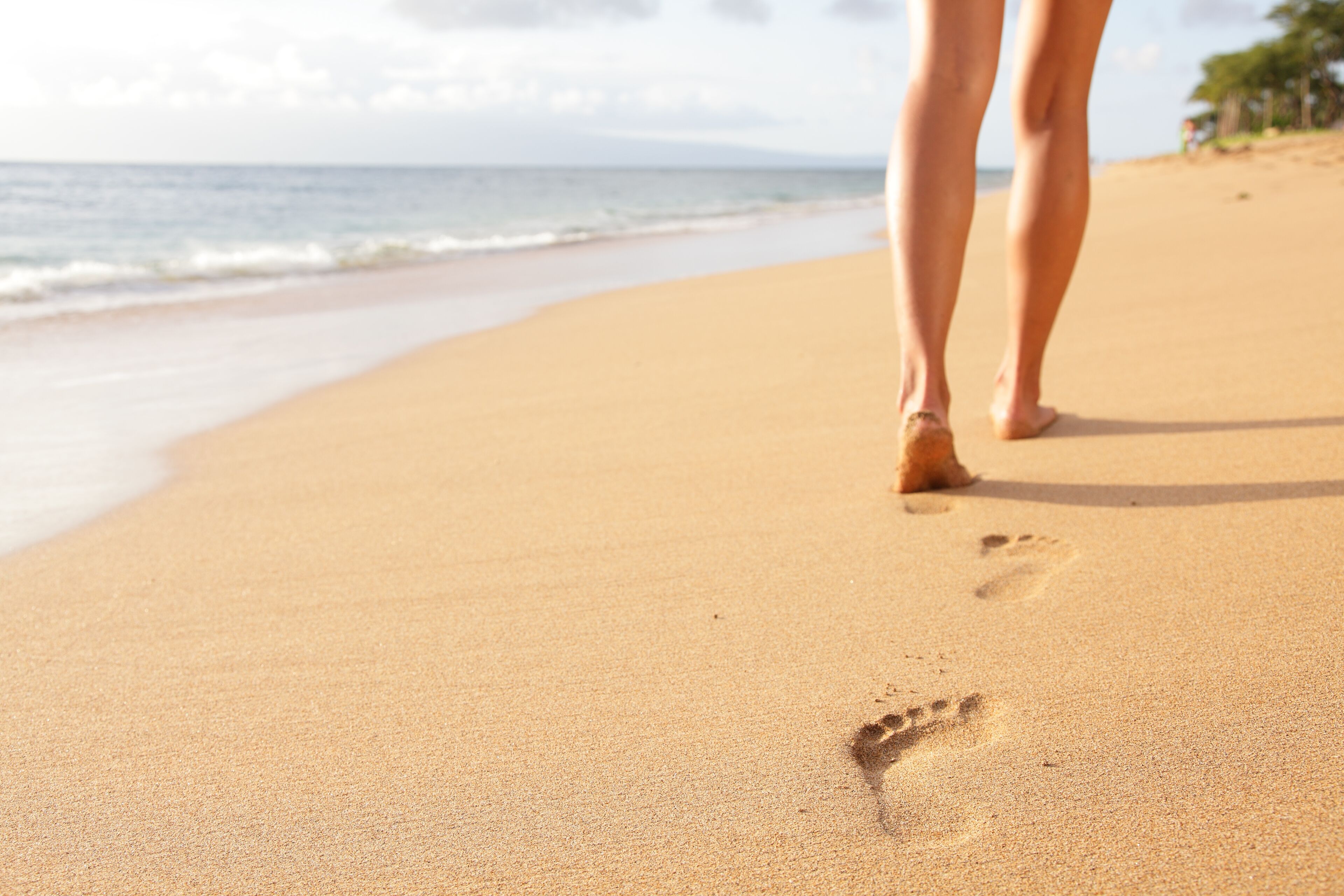 A sandy beach with footprints leading towards the ocean.