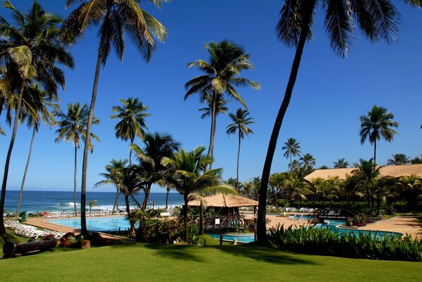 A resort with a pool, palm trees, and a view of the ocean. - Catussaba Resort Hotel (Salvador)