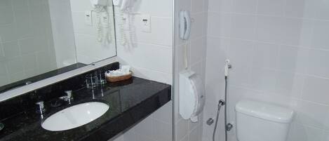 Ein Badezimmer mit Waschbecken, Spiegel, Fön, Telefon und Toilette.