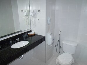 Un baño con lavamanos, espejo, secador de pelo, teléfono y retrete.