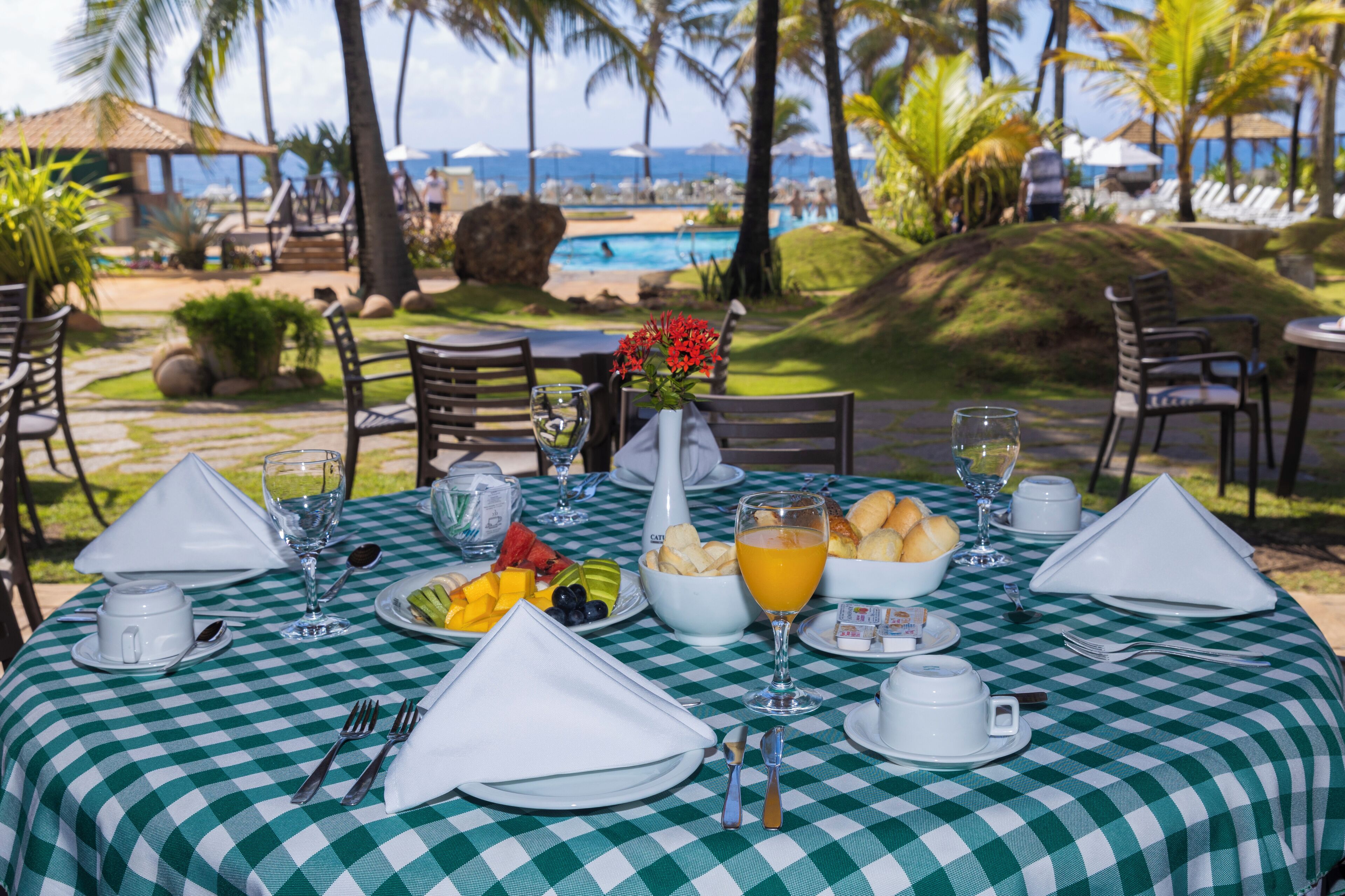 Una mesa lista para el desayuno con vista a una piscina y palmeras.