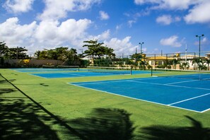 A tennis court with multiple courts, surrounded by trees and buildings. - Catussaba Resort Hotel (Salvador)