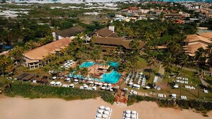 Vista aérea de un complejo turístico con playa, zona de piscina y varias edificaciones.
