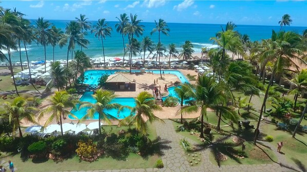 Un resort con piscina, palmeras y vista al mar.