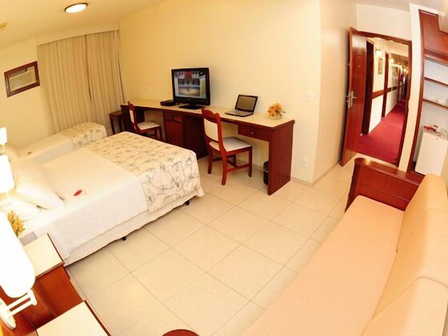 Une chambre d’hôtel comprenant un lit, un bureau avec un ordinateur, une chaise, un canapé et une salle de bain.