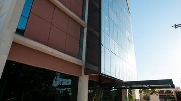 A modern building with a glass facade, a tiled entrance area, and potted plants.