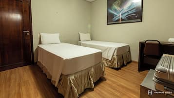 Habitación de hotel con dos camas, un escritorio, una silla y una maleta.
