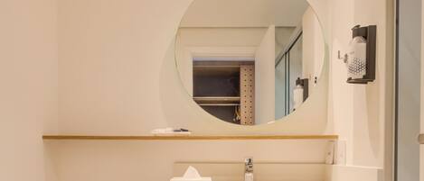 A modern bathroom with a toilet, sink, mirror, and towel storage.
