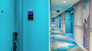 Passadís d'hotel amb decoració blava, indicadors de números de les habitacions i una catifes amb disseny.