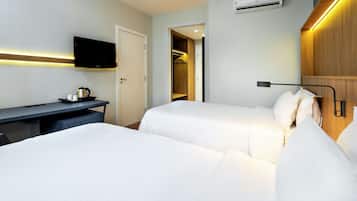 Quarto de hotel com duas camas, uma escrivaninha, televisão e guarda-roupa.